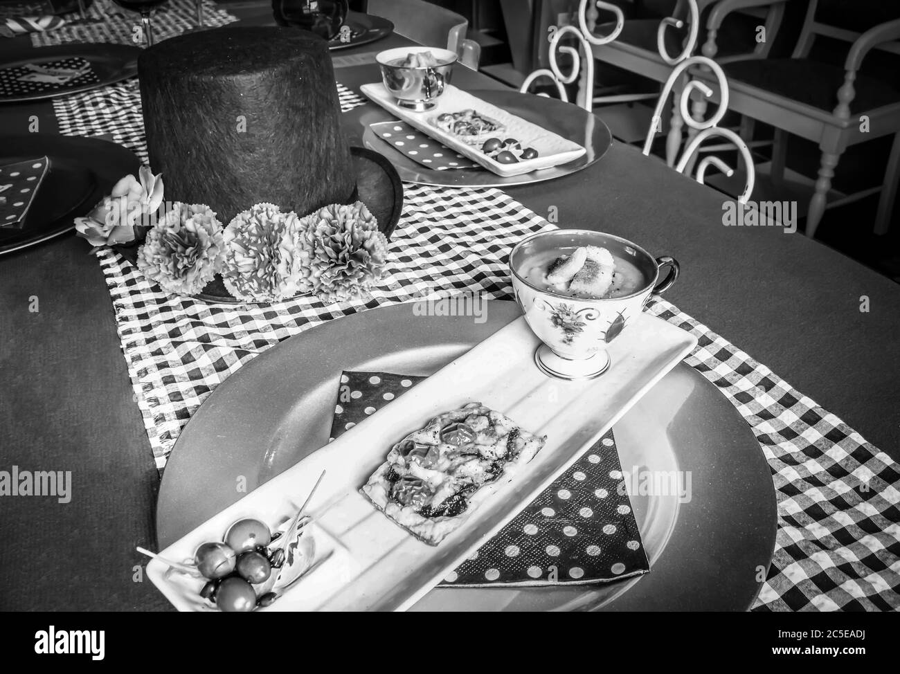Butternuss- und Kürbissuppe, Tomaten und karamellisierte Zwiebelteigkuchen mit Salat auf einem weißen rechteckigen Teller und einem runden goldenen Teller Stockfoto