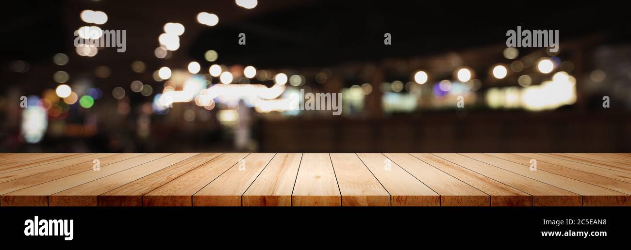 Panorama leere saubere Holz Theke Tischplatte auf Blur Street Nacht Café Hintergrund für Pub Coffee Shop Montage dunkle Szene, verschwommen breiten Holzstruktur Stockfoto