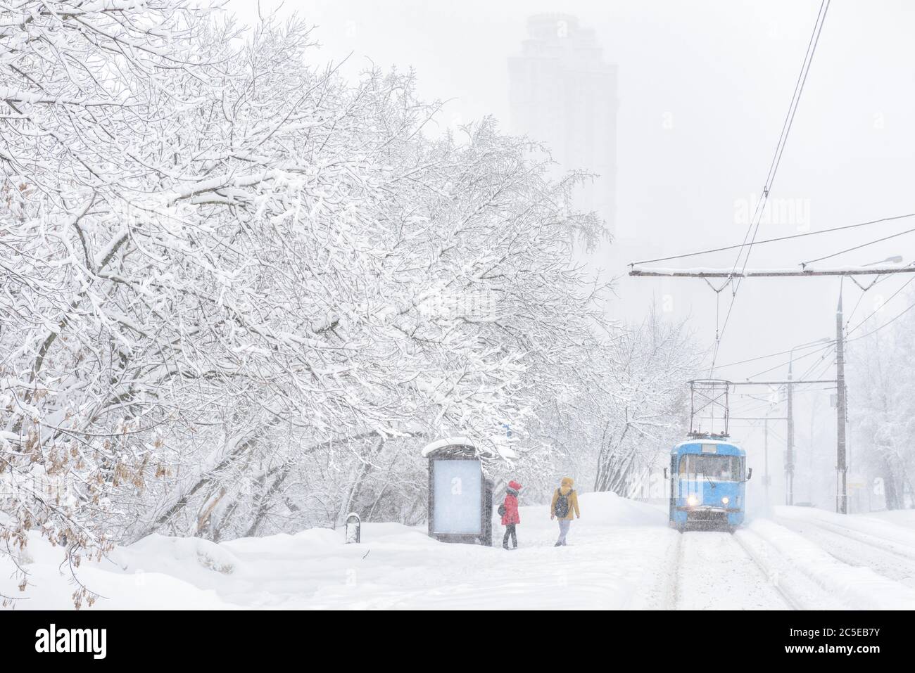 Tram fährt während Schneesturm im Winter, Moskau, Russland. Die Leute warten auf einen eisigen Stopp. Kälte und Schneefall in der Stadt. Landschaftlich reizvolle Panorama der Stockfoto