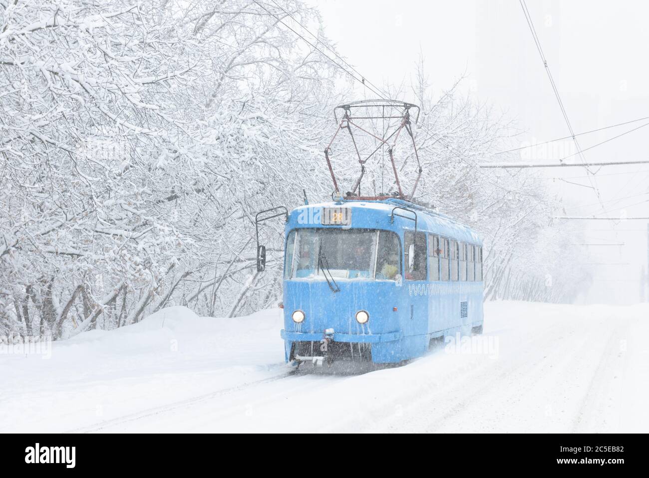 Tram geht entlang der Straße während Schneesturm im Winter in Moskau, Russland. Kälte und Schneefall in Moskau. Eisige Straßenbahn in verschneiten Moskau. Traditionelle Ansicht von Mo Stockfoto