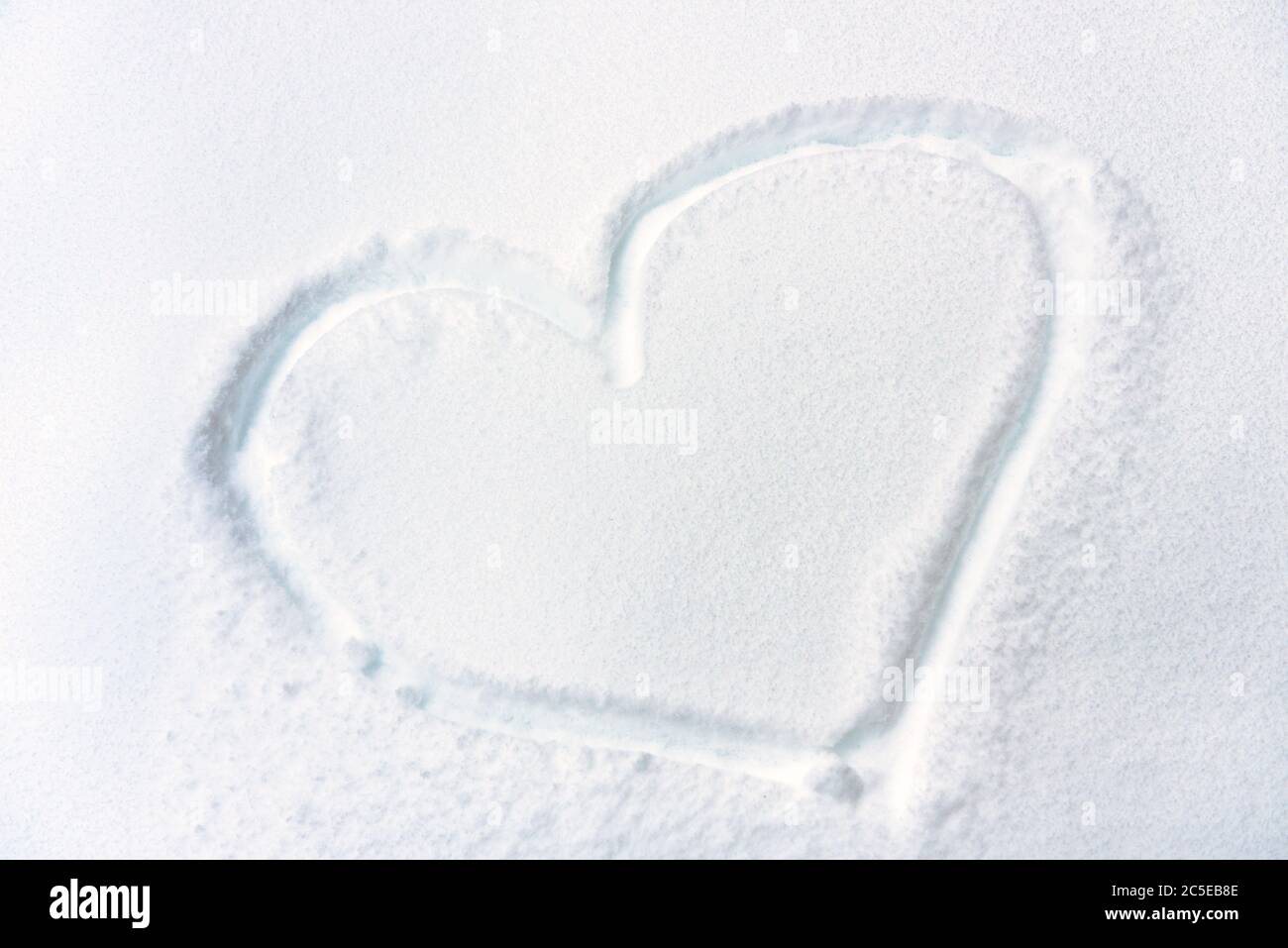 Herz auf frischer Schnee Textur gezeichnet. Symbol des Herzens auf verschneite Oberfläche Nahaufnahme. Konzept der Liebe, Romantik und Winterurlaub. Herzform auf weißem reinem BA Stockfoto