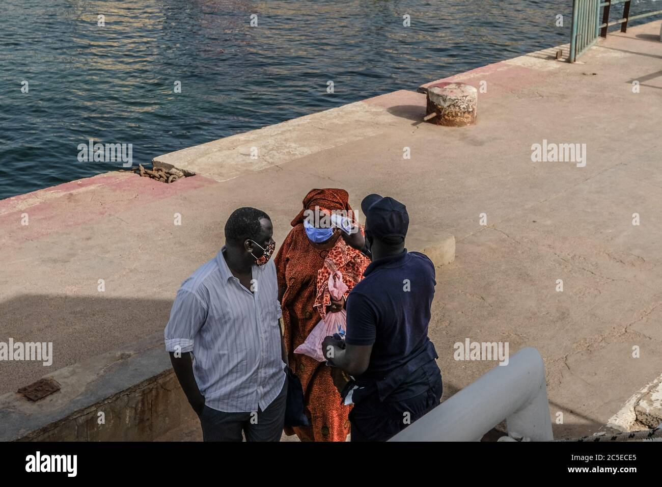 Dakar, Senegal. Juli 2020. Die Passagiere lassen sich vor dem Einsteigen in ein Shuttle-Boot nach Dakar auf der Insel Goree, Senegal, am 1. Juli 2020 die Temperatur überprüfen. Vier Monate nach Ausbruch der COVID-19-Pandemie am 2. März in Senegal haben die bestätigten Fälle am Donnerstag die Marke von 7,000 überschritten. Kredit: Eddy Peters/Xinhua/Alamy Live Nachrichten Stockfoto