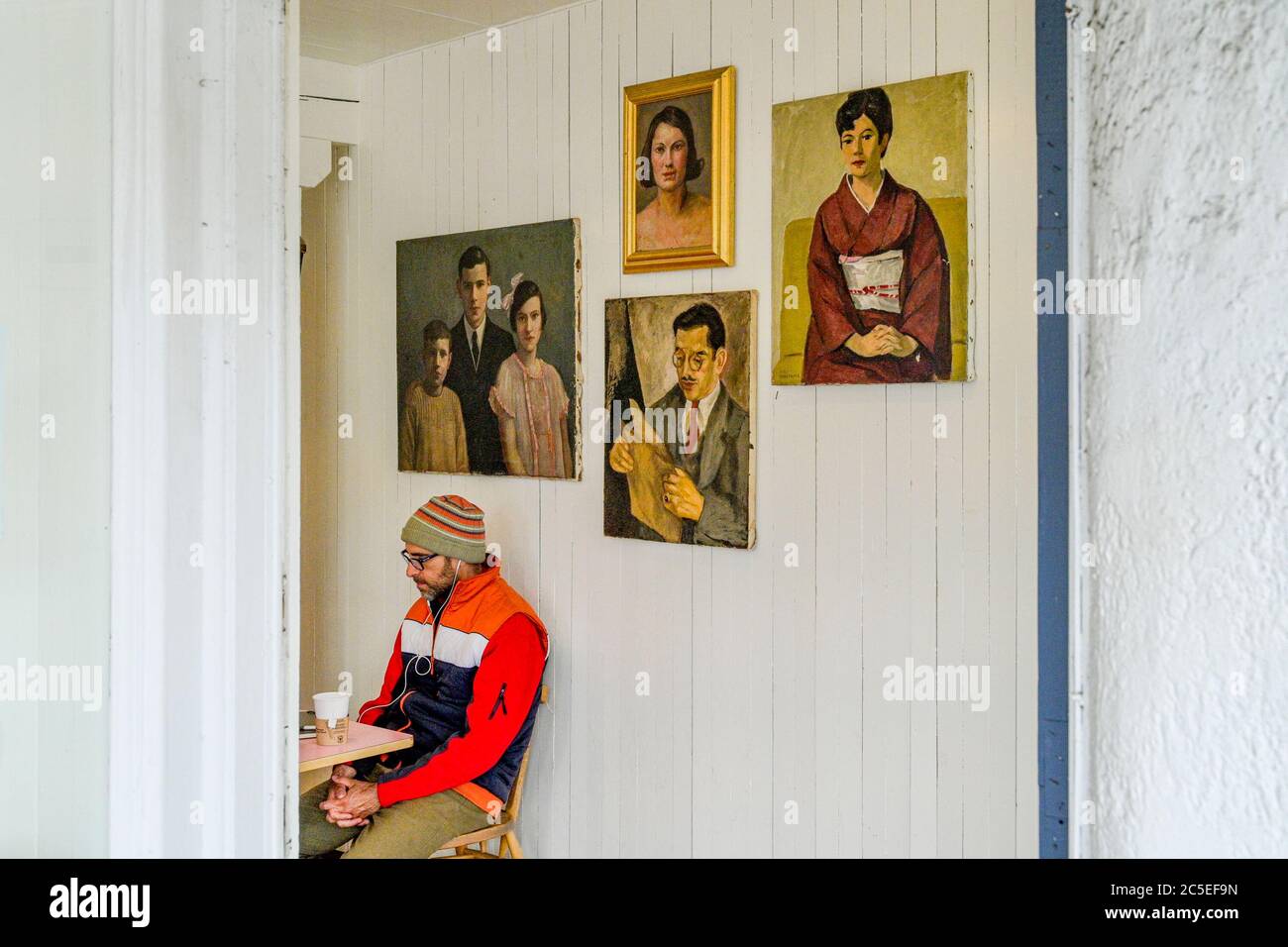 Porträt des Mannes im Café neben Porträts, Main Street, Vancouver, British Columbia, Kanada Stockfoto