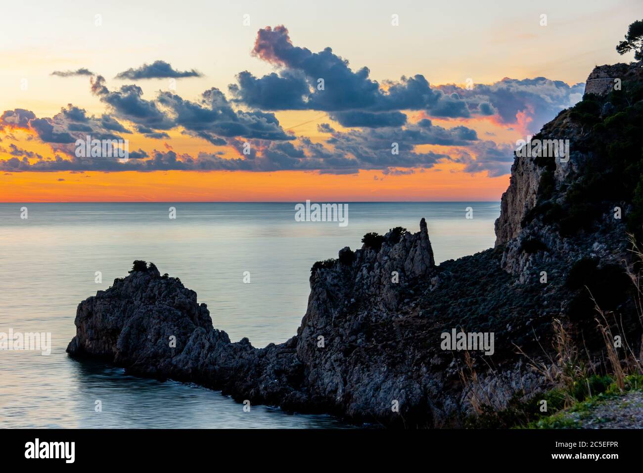 Felsküste der Riviera von Ulysses bei Sonnenuntergang, Bewölkt Red Sky auf dem Hintergrund. Sperlonga Italien. Hochwertige Fotos Stockfoto