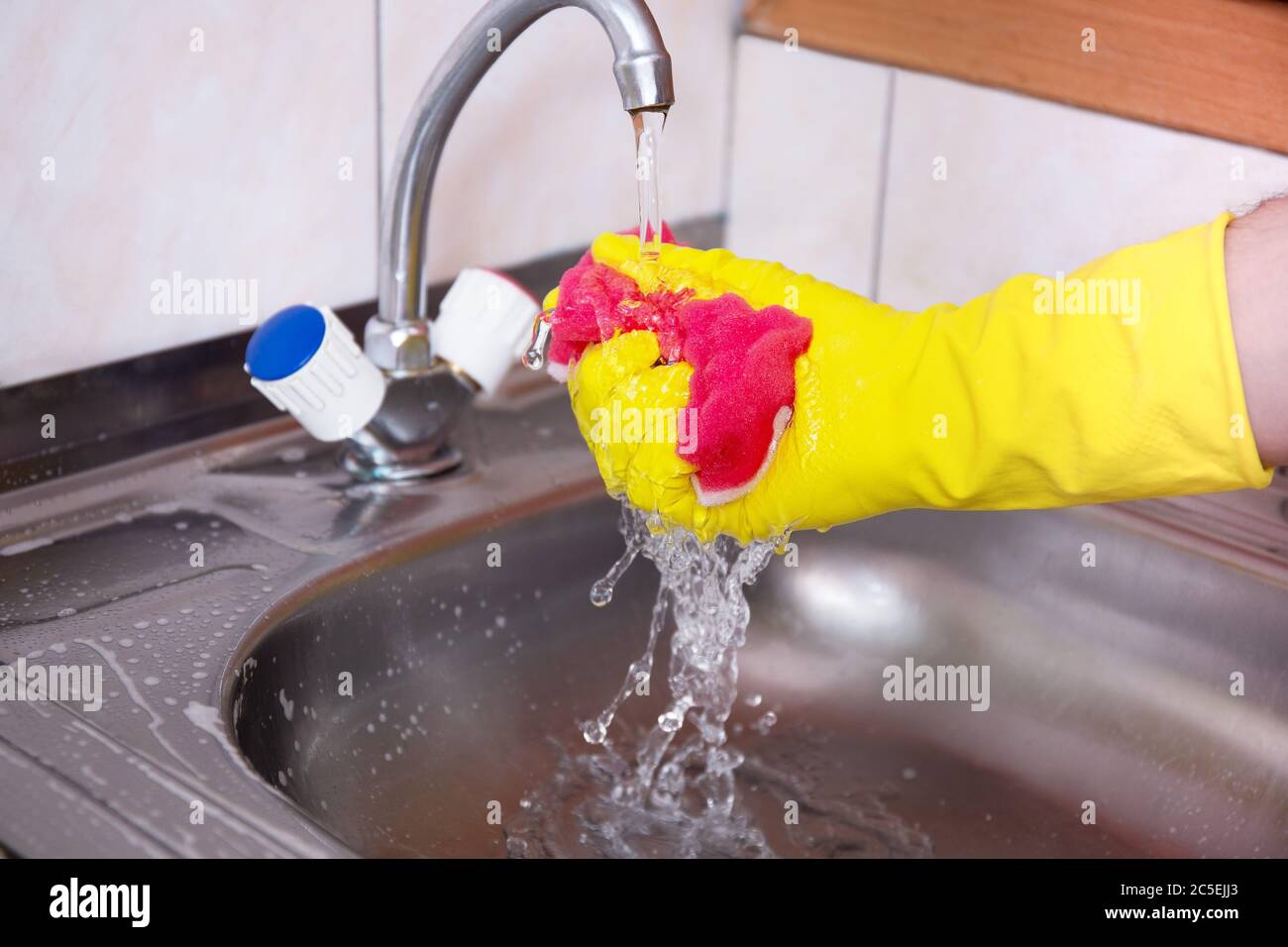 Hände in gelben Handschuhen reinigen Waschbecken mit Schwamm und einem  speziellen Reinigungsmittel, Waschmittelspray. Hygiene in der Küche,  Reinigung der Küche, Haushalt Stockfotografie - Alamy