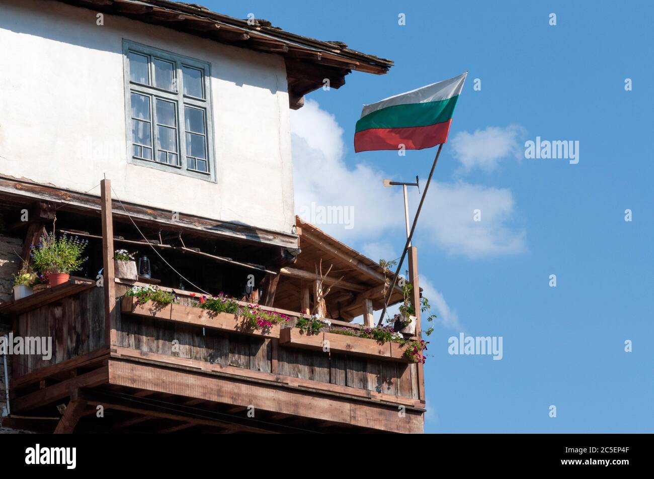 Die bulgarische Flagge fliegt auf dem Balkon eines traditionellen und authentischen Hauses im Stil der historischen Wiederbelebung des 19. Jahrhunderts in Kovachevitsa, Bulgarien Stockfoto