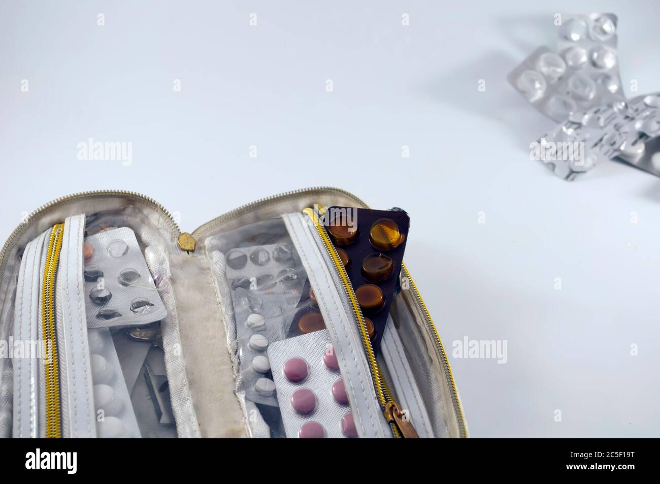 Weiße Handtasche, mit halbleeren Tablettenblasen auf weißem Hintergrund, leere Blasen in der oberen rechten Ecke Stockfoto