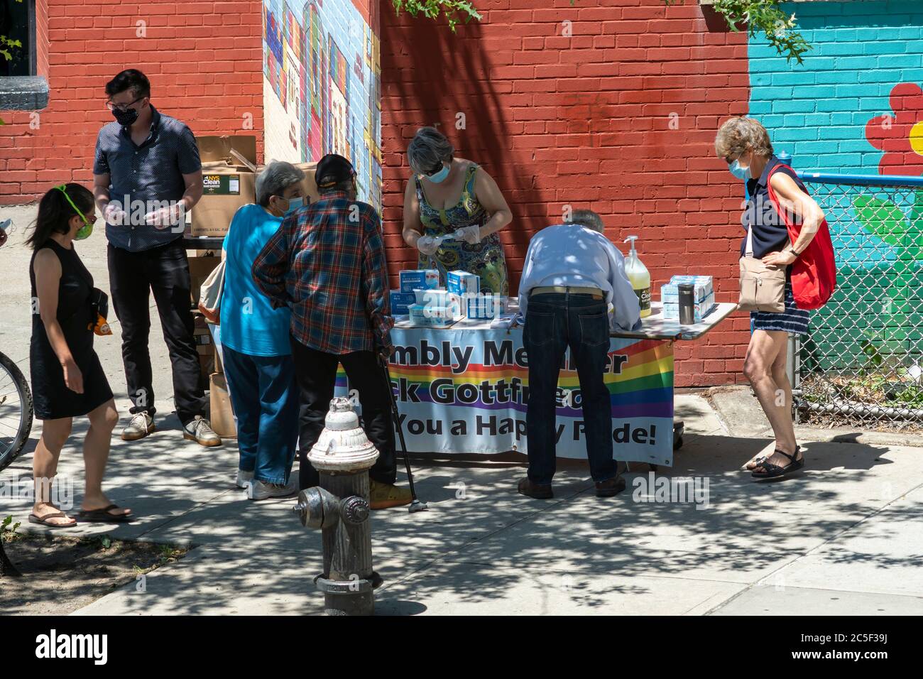 Die New Yorker holen am Donnerstag, den 25. Juni 2020, an einem Tisch des NYS-Vereinen Richard Gottfried im New Yorker Stadtteil Chelsea kostenlose Masken und Handdesinfektionsmittel ab. (© Richard B. Levine) Stockfoto