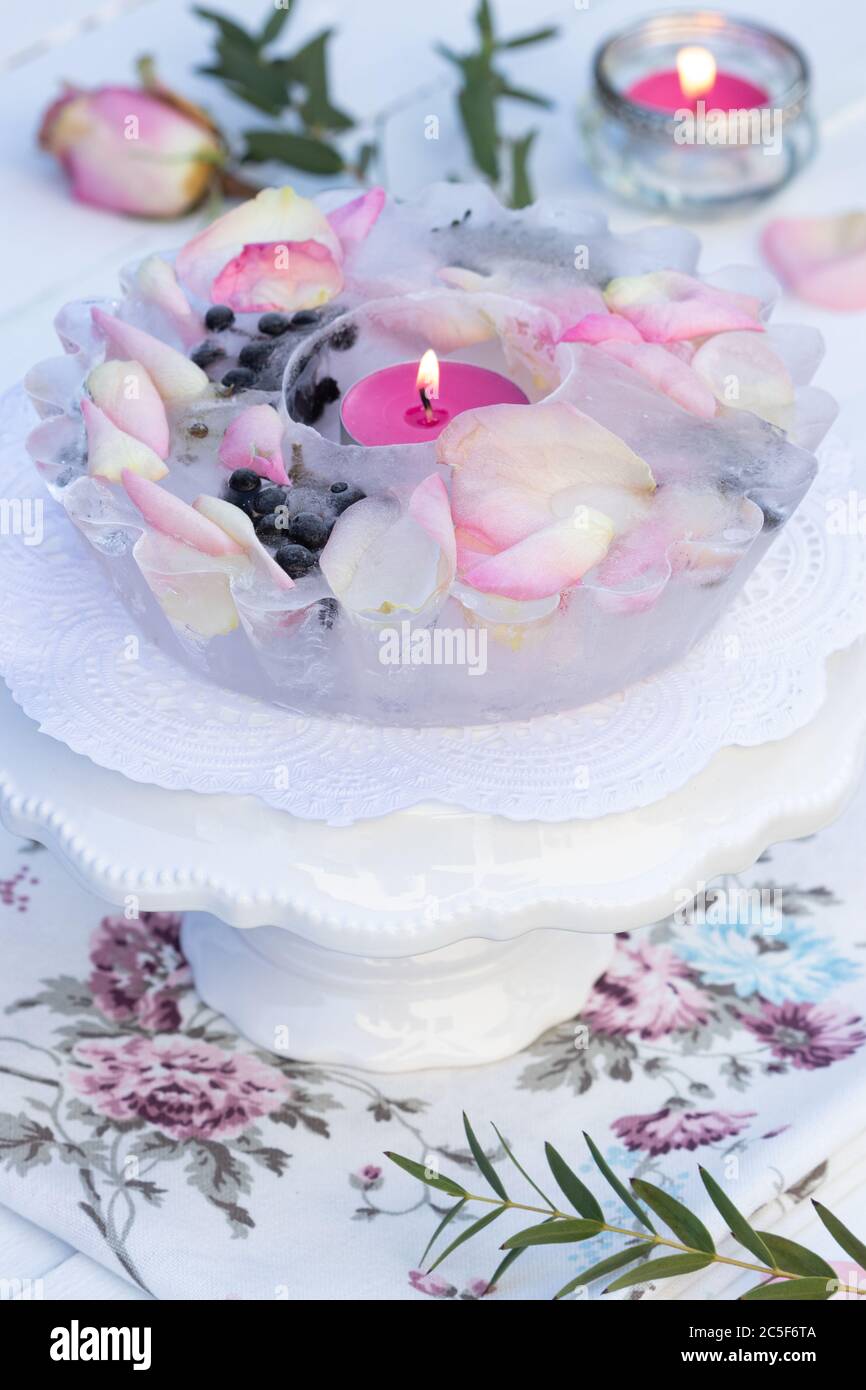 Eislaterne mit Rosenblättern als Garten-Winterdekoration Stockfoto