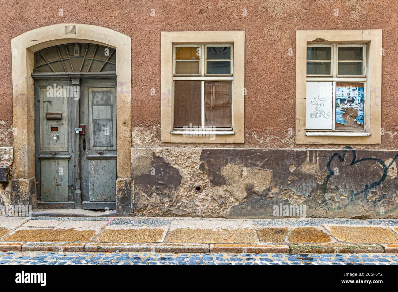 Verblasste Fassade mit Tür und kaputten Fenstern in Görlitz, Deutschland Stockfoto