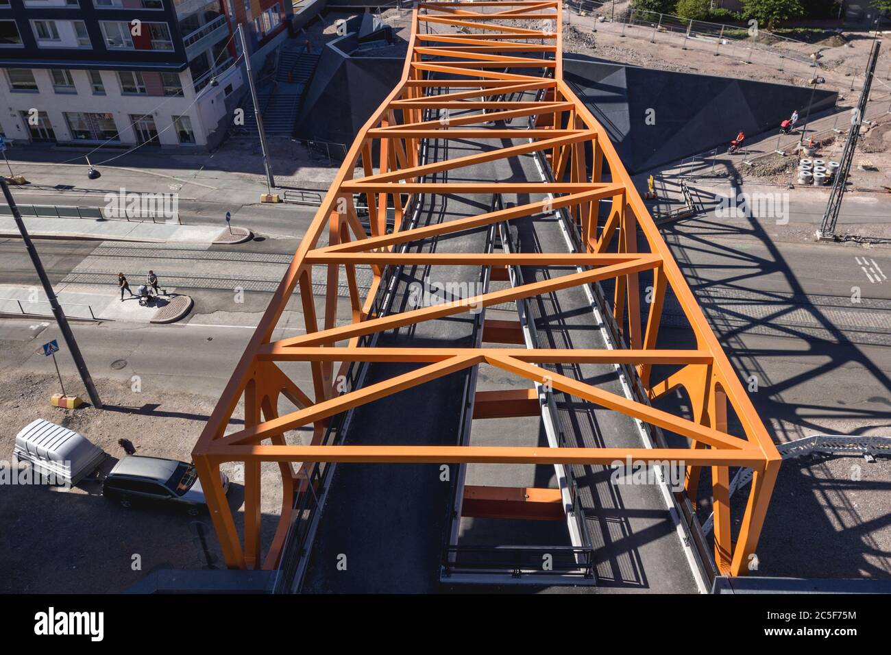 Luftaufnahme der Fußgängerbrücke über die Straße und die Straßenbahnschienen im Jatkasaari-Viertel, Helsinki, Finnland. Stockfoto