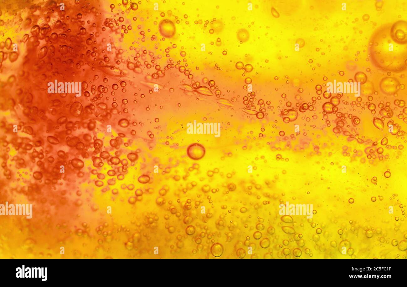 Abstrakter strukturierter Gelhintergrund. Gelbe und orange Flüssigkeit mit Blasen. Makroaufnahme mit weichem Fokus. Stockfoto