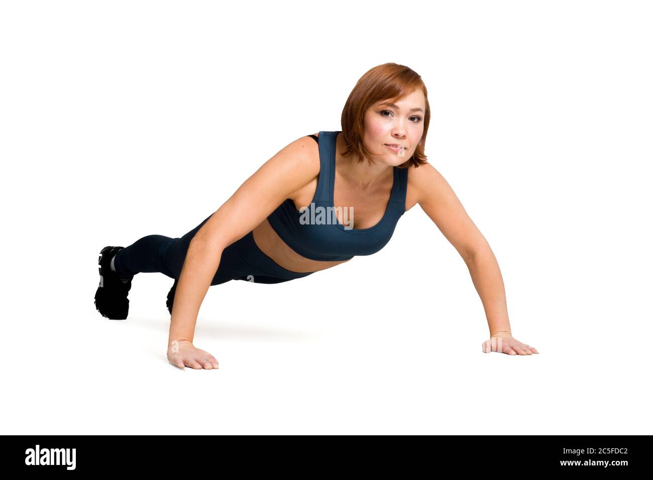 Gesunde Fitness-Frau mittleren Alters in klassischer blauer Sportbekleidung, Push-ups vom Boden auf weißem Hintergrund zu isolieren Stockfoto