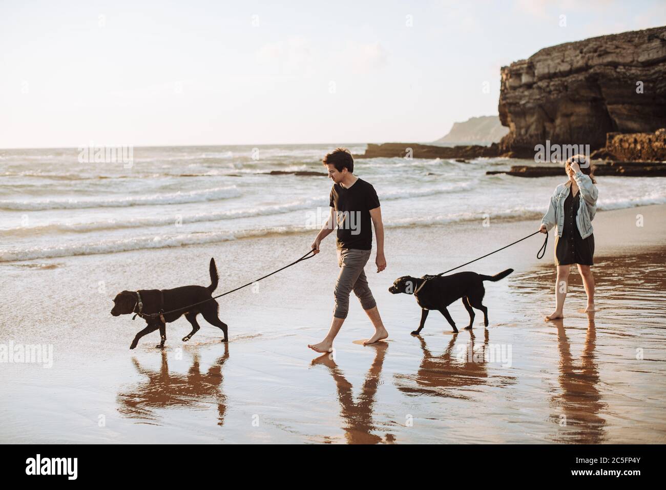 Paar mit Hunden am Strand spazieren, romantischer Kurzurlaub in Portugal Stockfoto