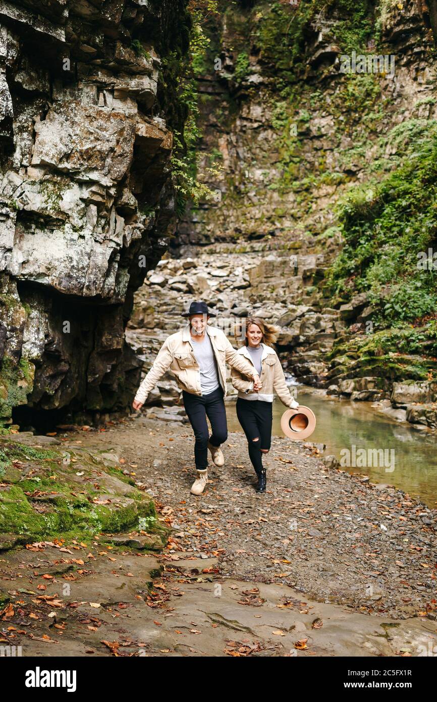 Junges und schönes Paar am Bergwasserfall - Glückliche Touristen, die Berge besuchen. Liebe. Touristen in Hüten. Militärische Mode Stockfoto