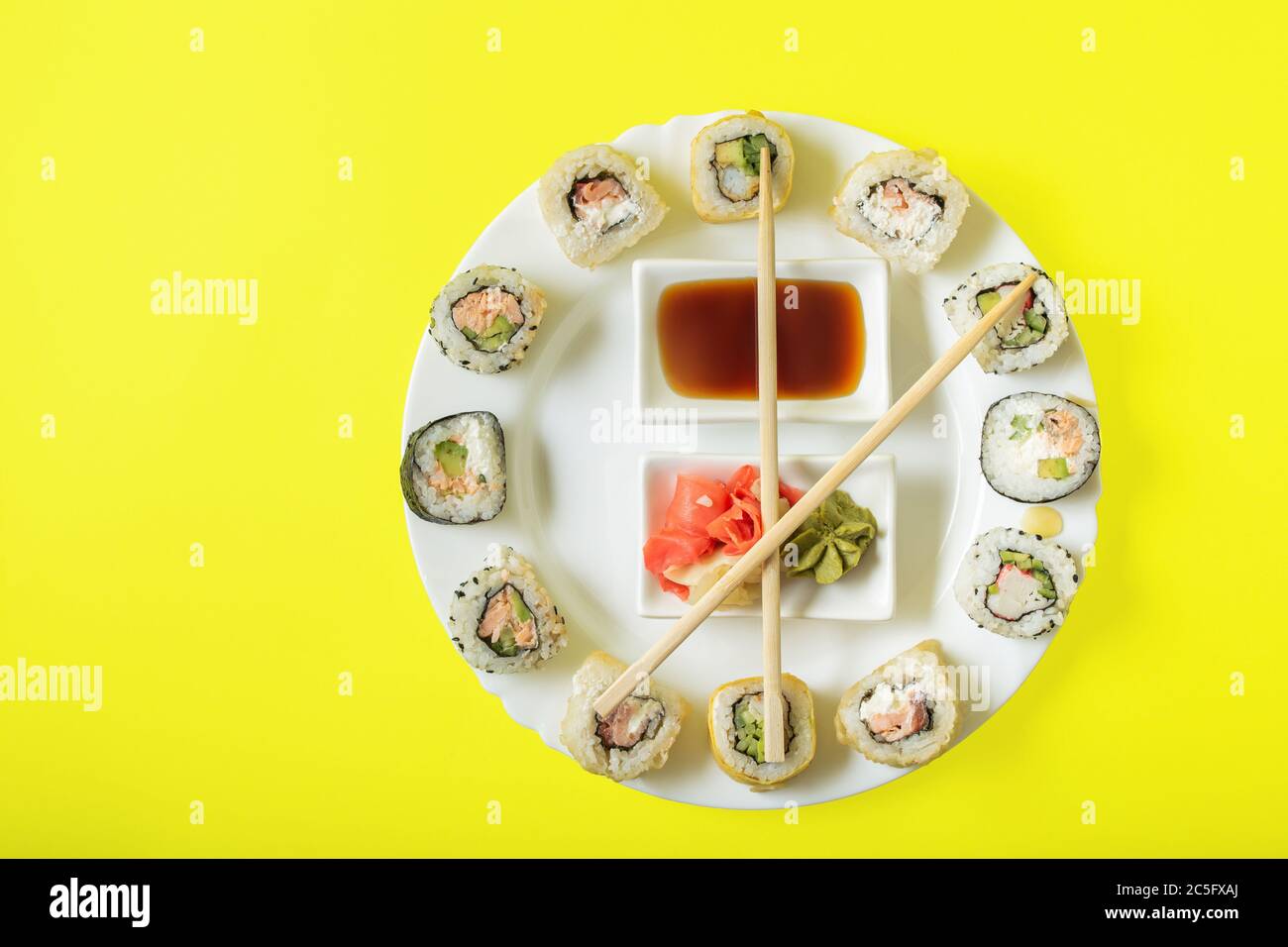 Sushi-Zeit in Form einer Wanduhr auf einem konkreten Hintergrund. Sushi-Uhr. Stockfoto