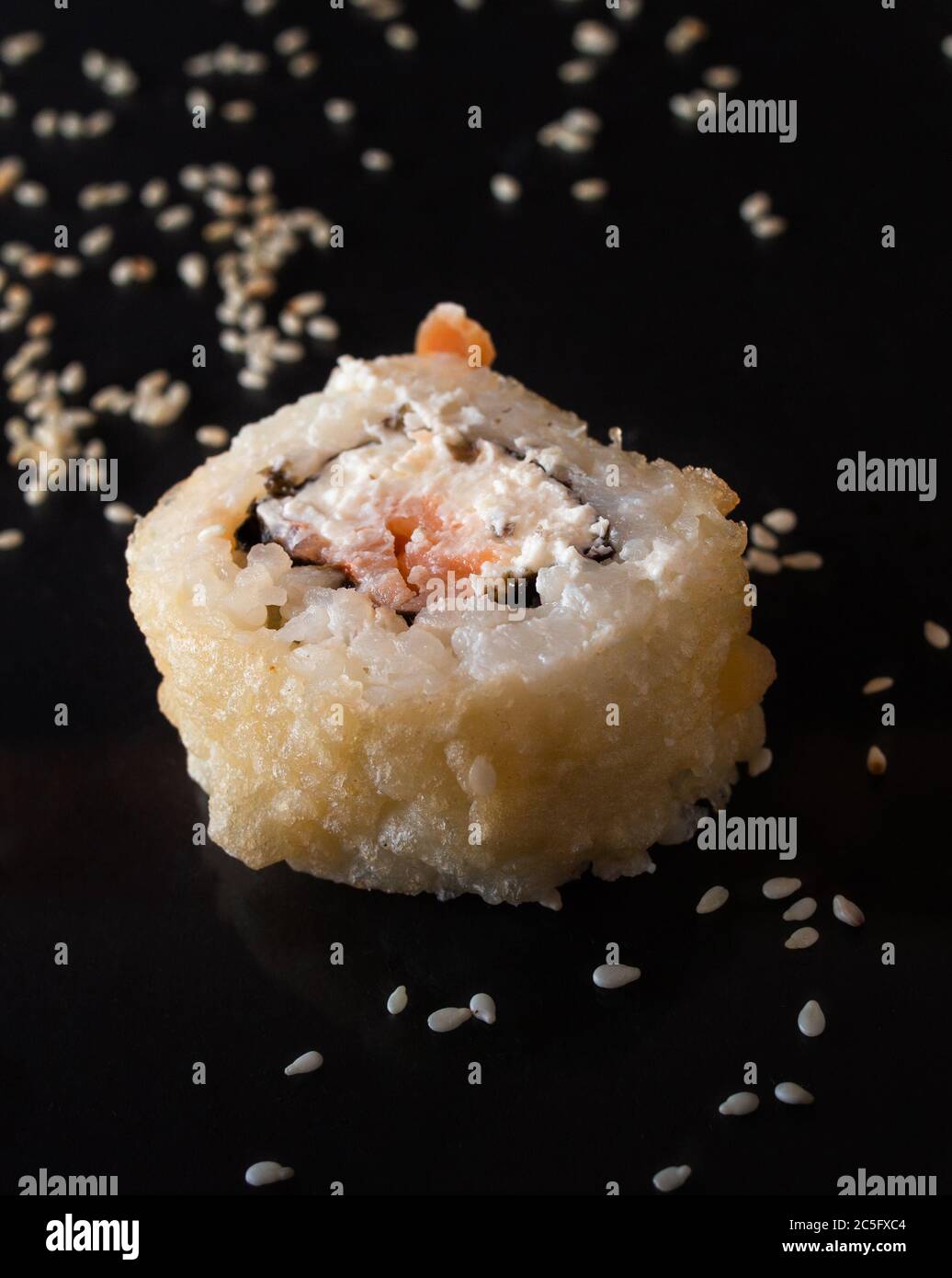 Frisches, leckeres Sushi mit Avocado, cremigem Käse, Lachs und auf Schwarz mit Spiegelung isoliert Stockfoto
