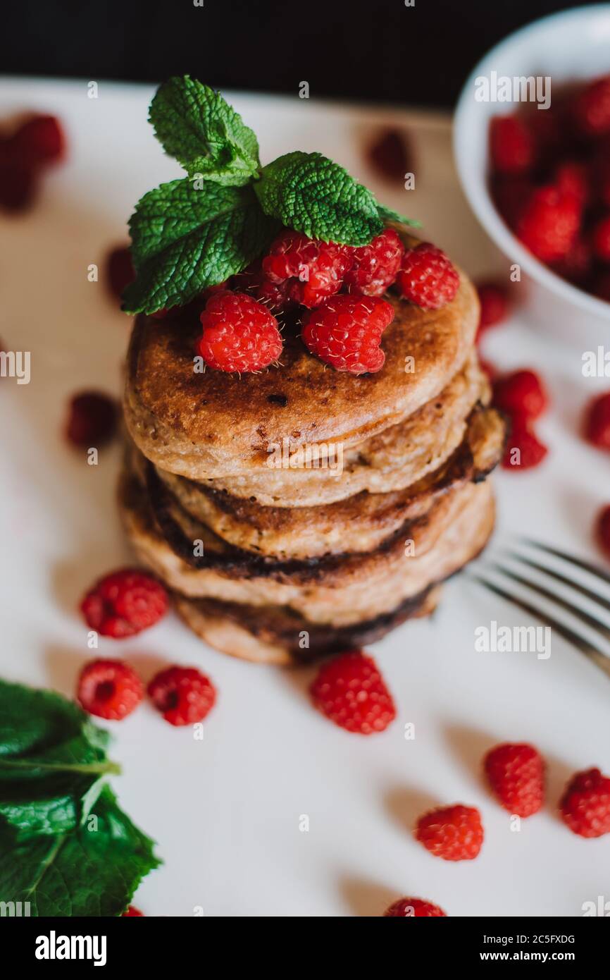 Schokoladen-Pfannkuchen mit frischen Himbeeren und Minze auf schwarzem Hintergrund Stockfoto