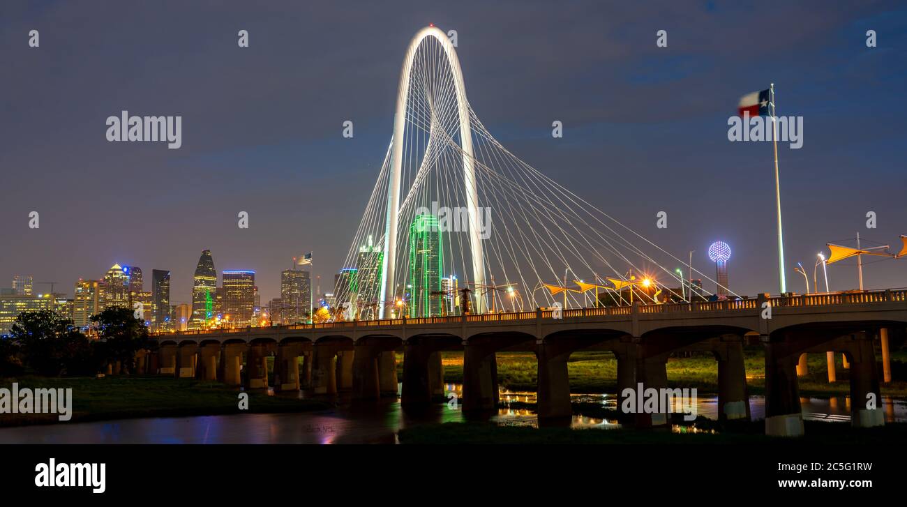 Blick auf die Margaret Hunt Hill Bridge bei Nacht mit Texas Flag und Reunion Tower im Hintergrund Stockfoto