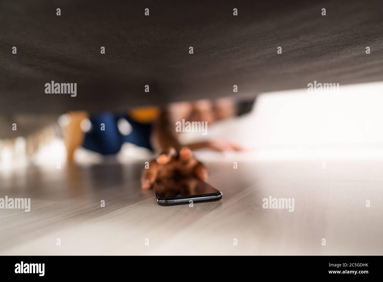 Mädchen Auf Der Suche Nach Verlorenen Handy Unter Sofa Stockfoto