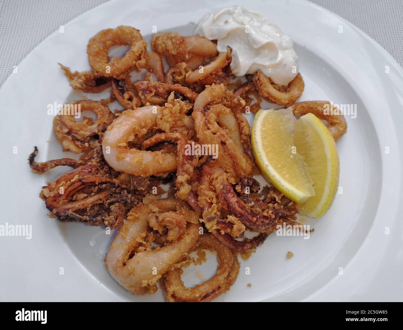 Gebratene Calamari Ringe mit Sauce und Zitrone, leckere Tintenfische, Oktopus Stockfoto