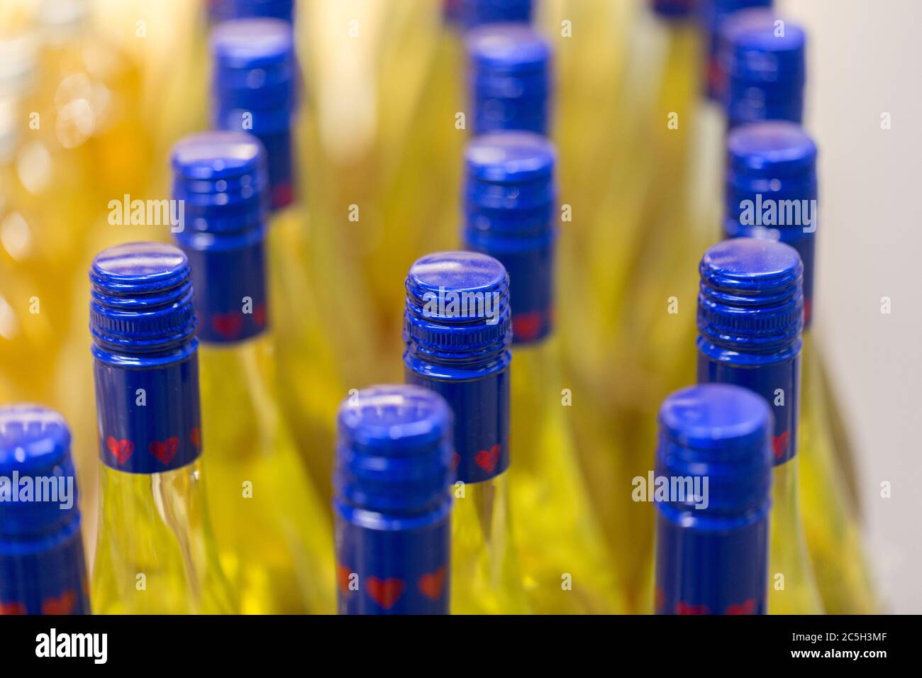 Nahaufnahme / Makro von Flaschen mit blauer Kappe mit einer gelben Flüssigkeit. Herzformen sind auf der Kappe aufgedruckt. Hintergrund, Textur, Muster. Stockfoto