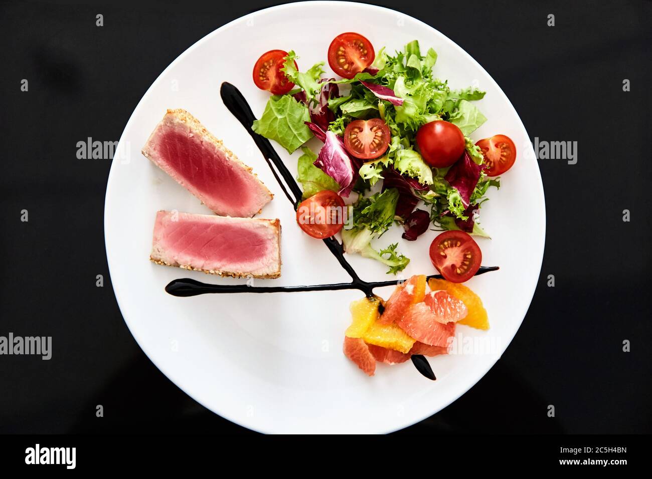 Mittelseltenes Hühnerfilet mit Tomatensalat. Schale auf schwarzem Hintergrund. Stockfoto