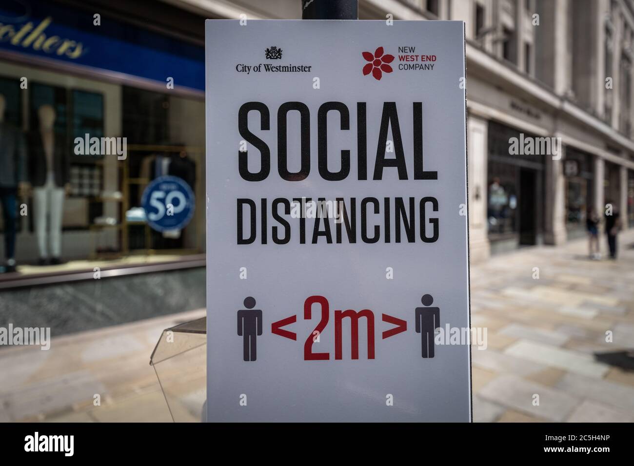 Social Distancing 2m Awareness-Schild auf der Oxford Street. Befristete Maßnahmen zum Schutz von Unternehmen und Straßenbenutzern. London, Großbritannien. Stockfoto