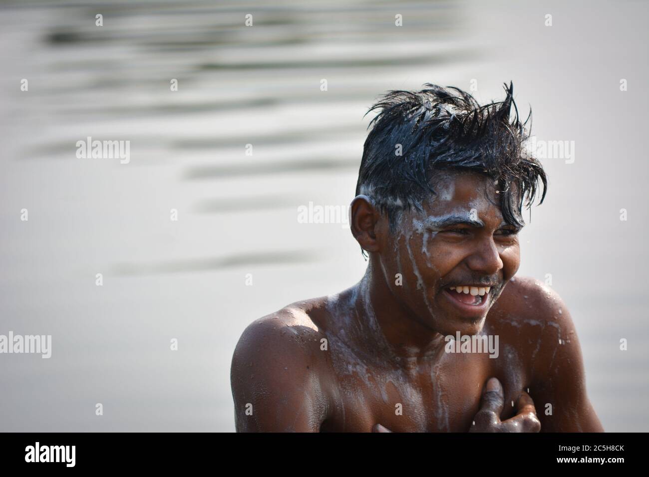 TIKAMGARH, MADHYA PRADESH, INDIEN - 13. NOVEMBER 2019: Indischer Dorfjunge, der morgens im Fluss badet, Körper und Haare mit Shampoo wäscht. Stockfoto