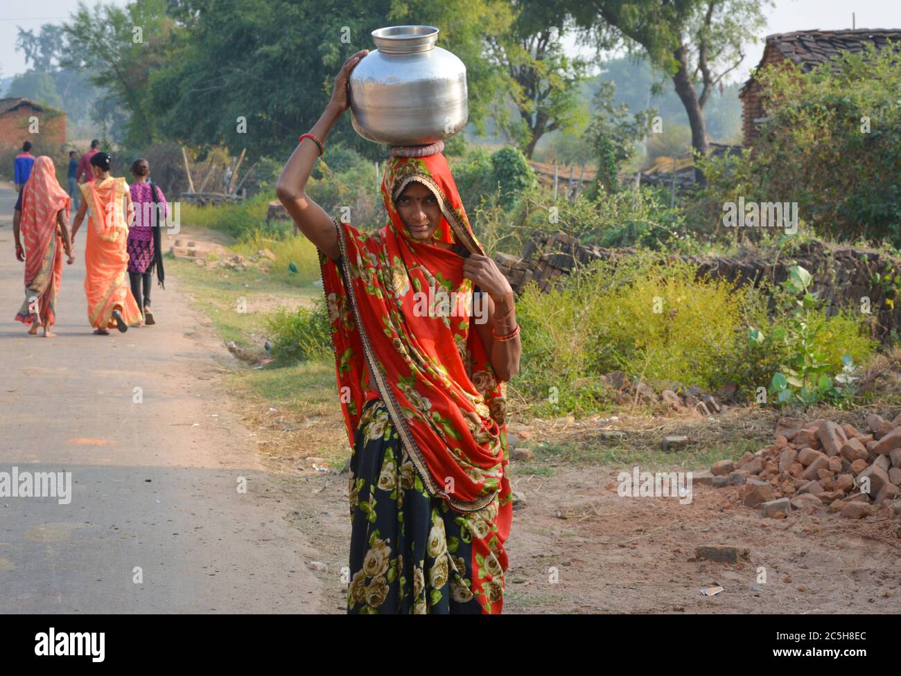 TIKAMGARH, MADHYA PRADESH, INDIEN - 12. NOVEMBER 2019: Eine nicht identifizierte indische Dorffrau trägt Wasser auf ihren Köpfen in traditionellen Töpfen aus Brunnen. Stockfoto