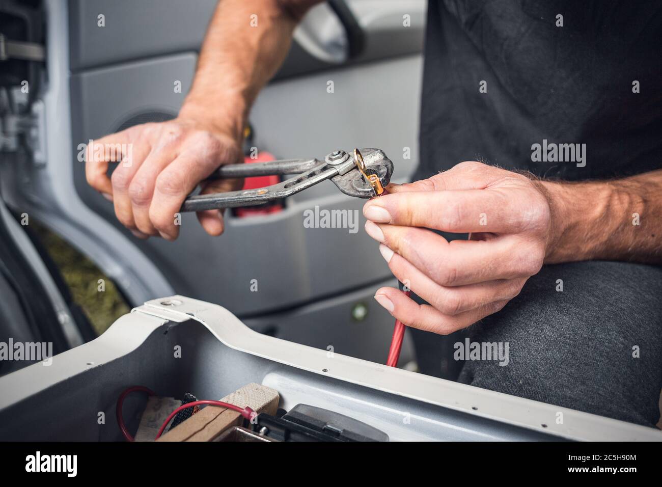 Mann, der an einem elektrischen Kabel in einem Wohnmobil arbeitet Stockfoto