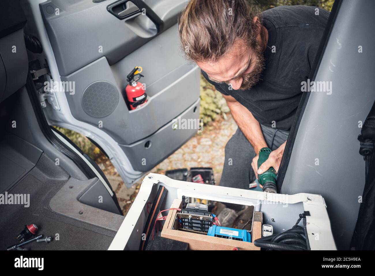 Man Customizing ein van - Integration von Elektronik in einen Vordersitz Stockfoto