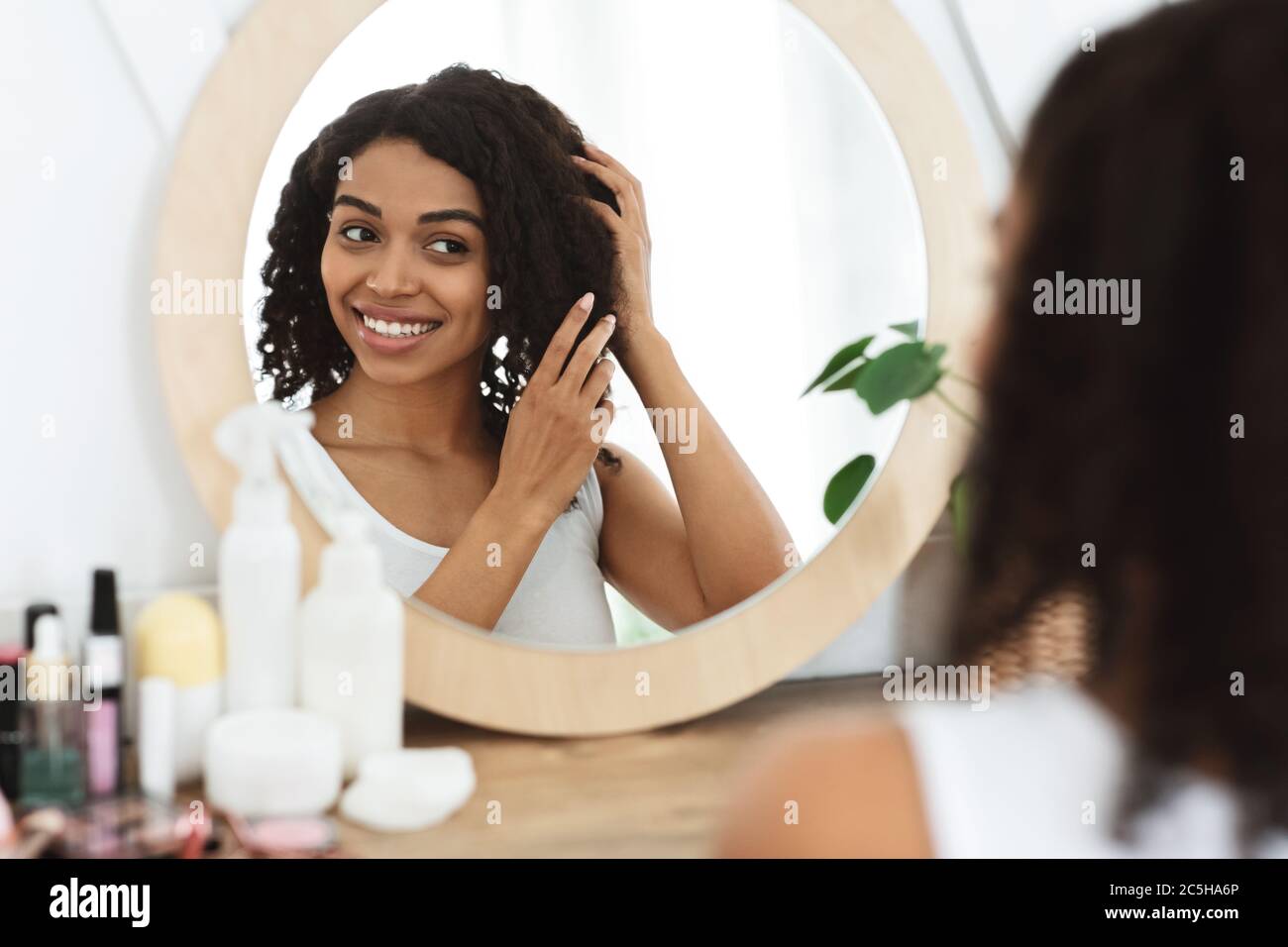 Natürliche Schönheit. Glücklich Schwarz Mädchen Berühren Sie Weich Lockiges Haar In Der Nähe Spiegel Stockfoto