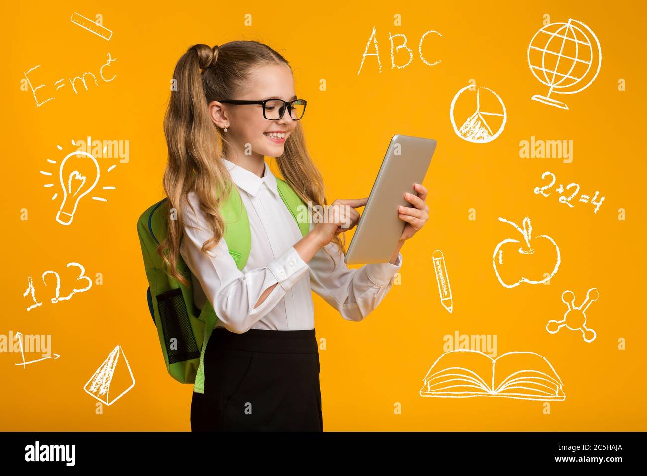 Bildung und Gadgets. Nettes Schulmädchen in Brille mit Tablet, um Symbole der Bildung Stockfoto