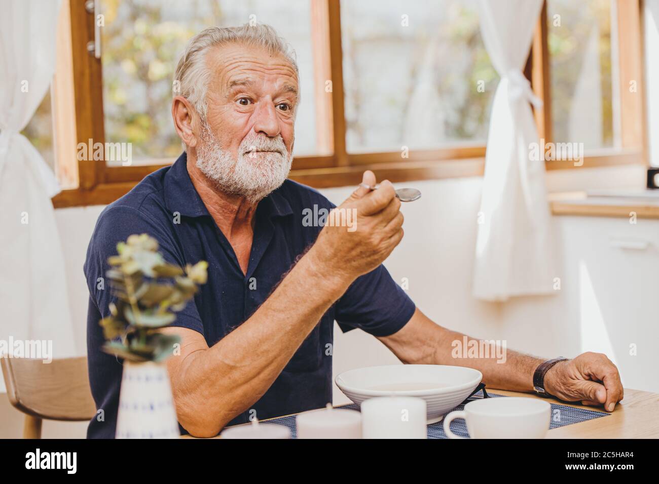 Elder Essen Gesichtsausdruck Fühlen Sie sich überraschen mit sehr guten Geschmack von Essen von seiner Frau Stockfoto
