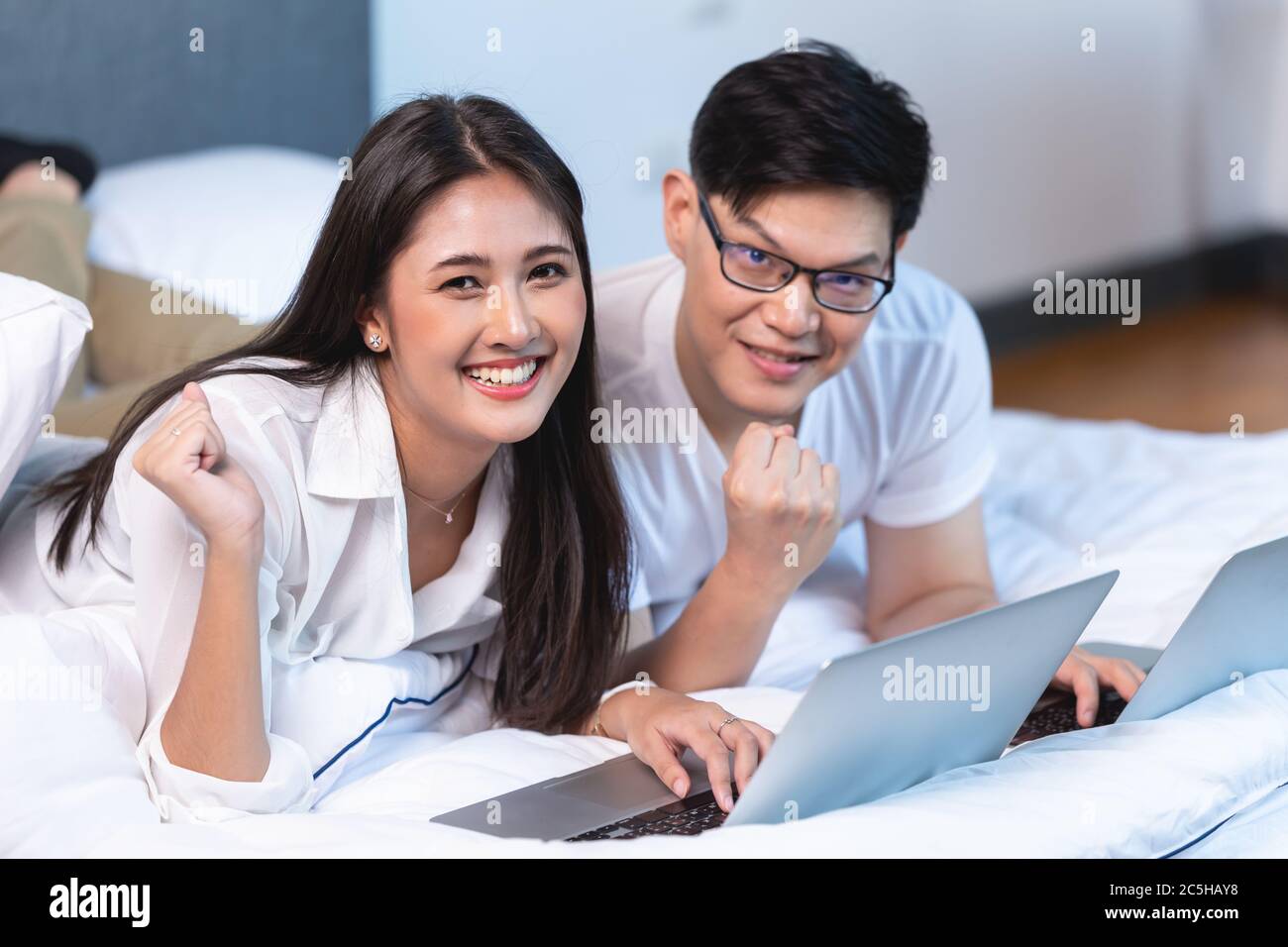 Asiatische Business-Paar Team arbeiten zu Hause auf dem Bett mit Laptop glücklich genießen mit Erfolg Porträt suchen Kamera. Stockfoto