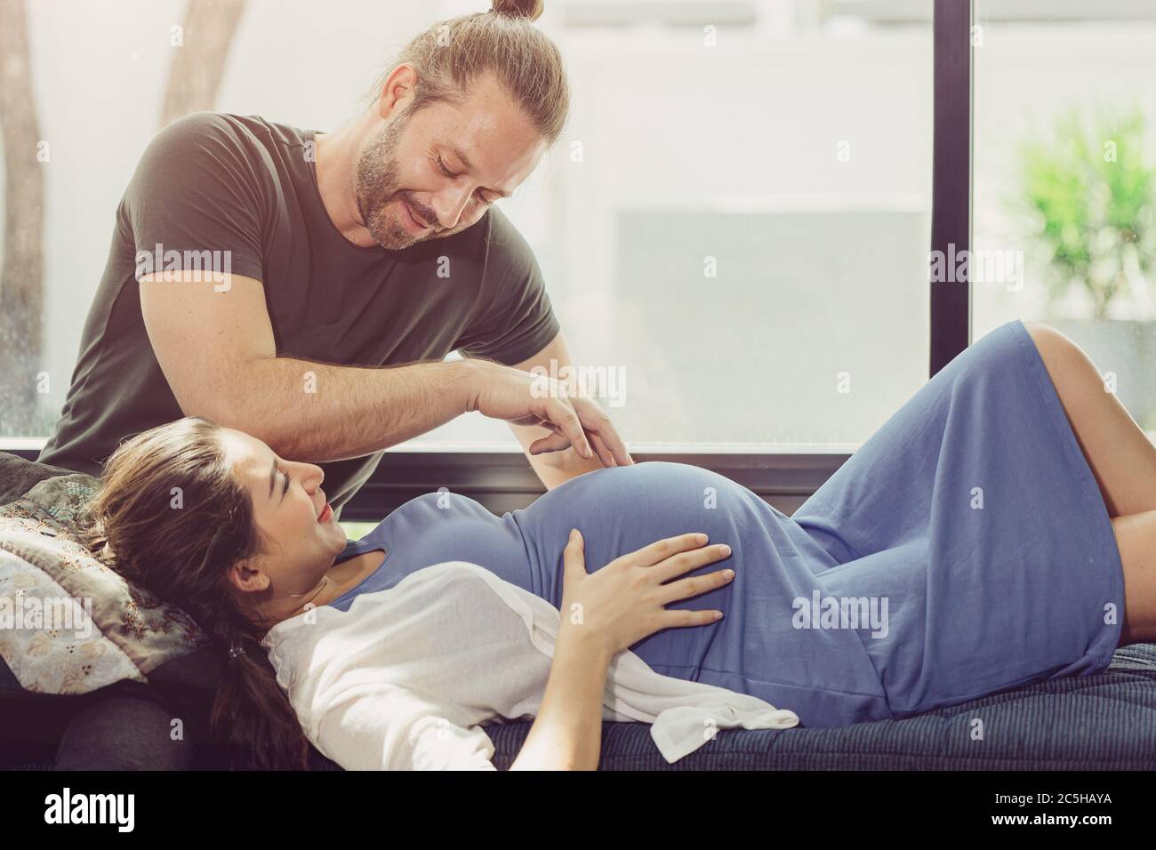 Pregnantzy Frau zu Hause bleiben mit schönen Mann niedlich spielen mit Baby Bauch. Stockfoto