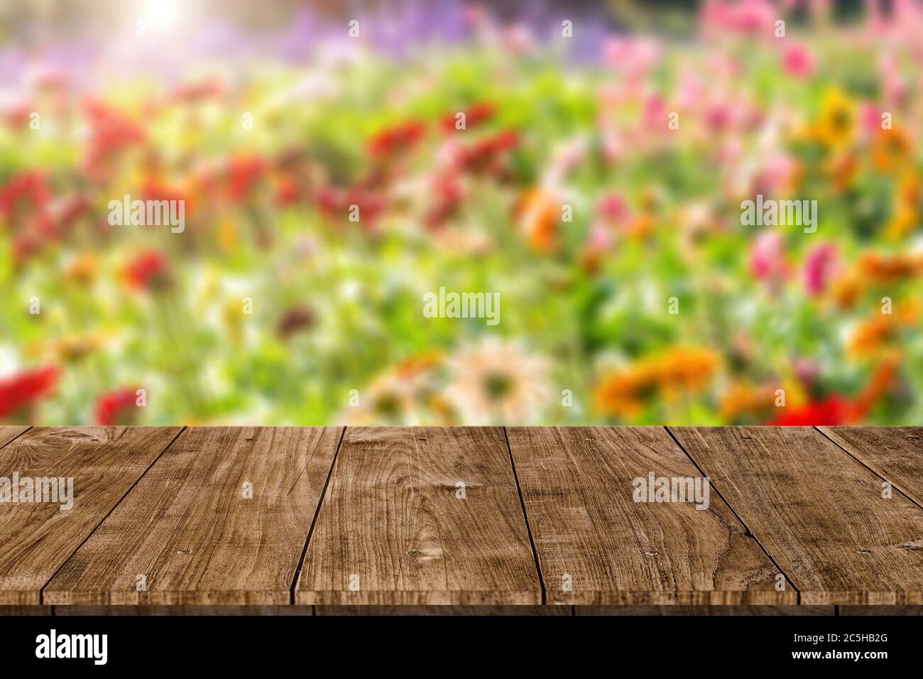 Blur bunte Blumenfeld mit Holztisch Platte leeren Raum für natürliche Aroma oder Parfüm Produkte Werbung Montage Vorlage. Stockfoto