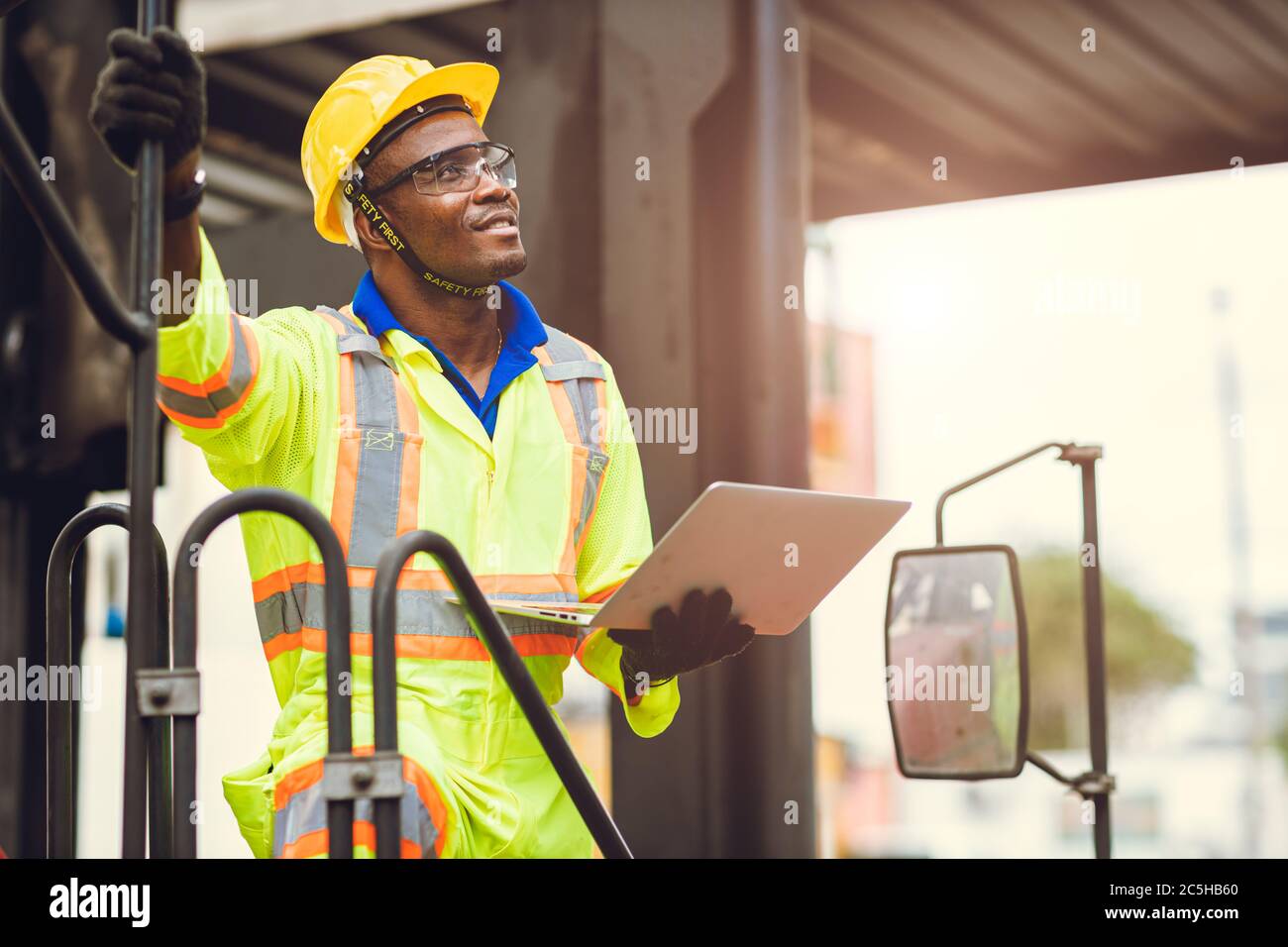 Black African American Arbeiter als Mitarbeiter Vorarbeiter stolz auf glücklich Lächeln Arbeit Kontrolle Verladung Fracht in Versand logistischen Lager mit Sicherheitsanzug. Stockfoto