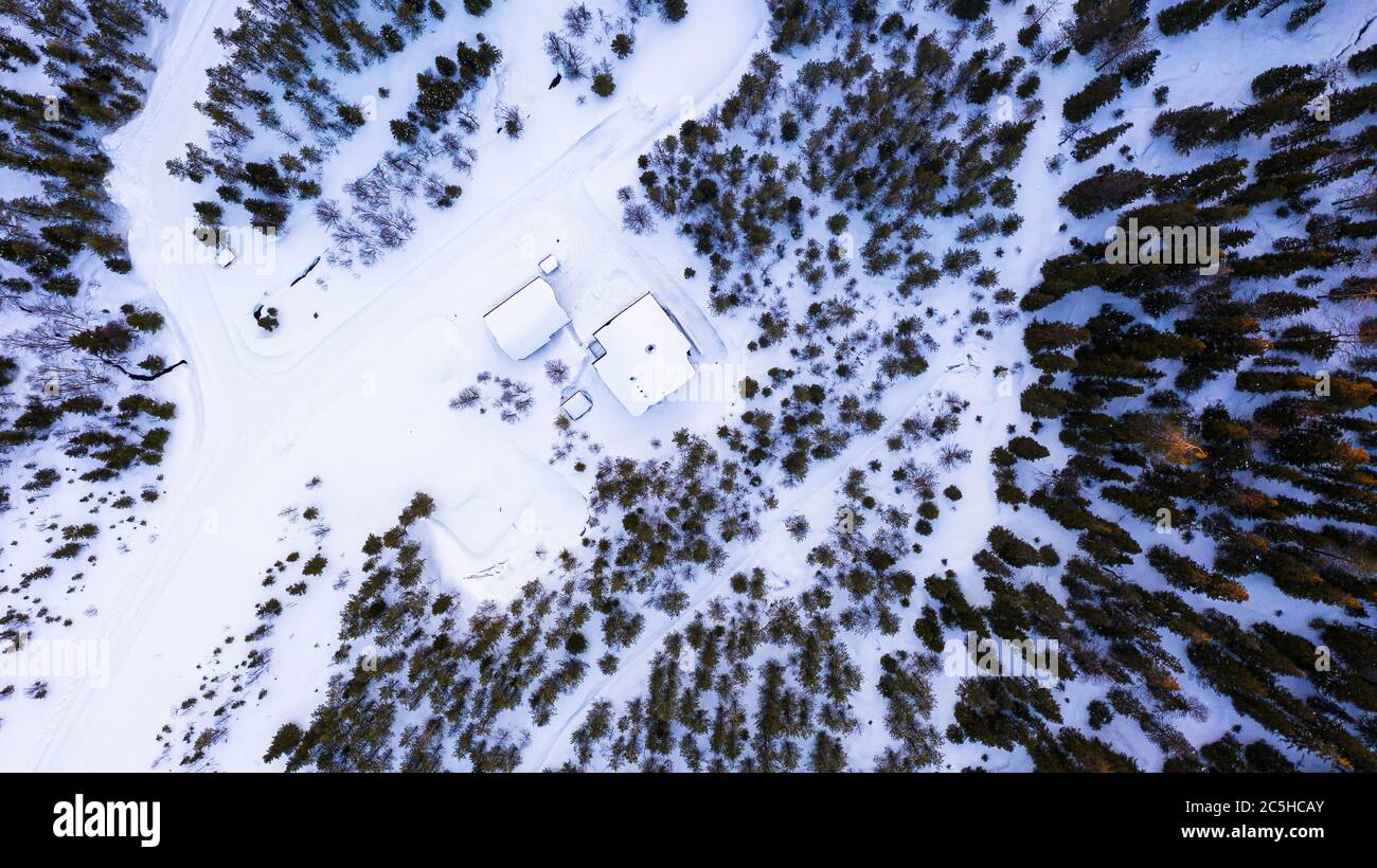 Luftaufnahme von oben nach unten eines mit Schnee bedeckten Hauses im Wald Stockfoto
