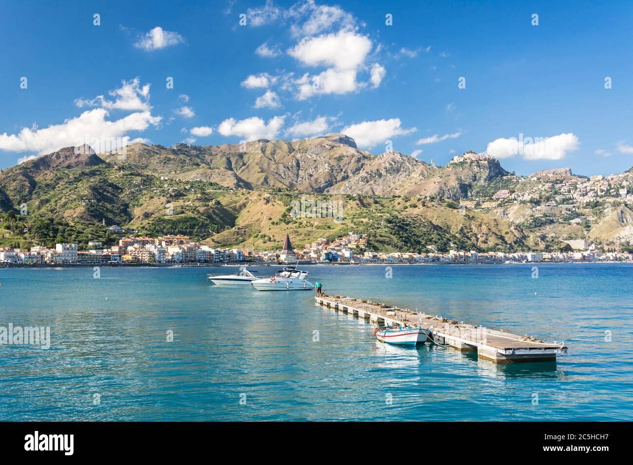 Holzsteg und einige Boote in schöner Bucht mit Bergen im Hintergrund auf der Insel Sizilien in Italien Stockfoto