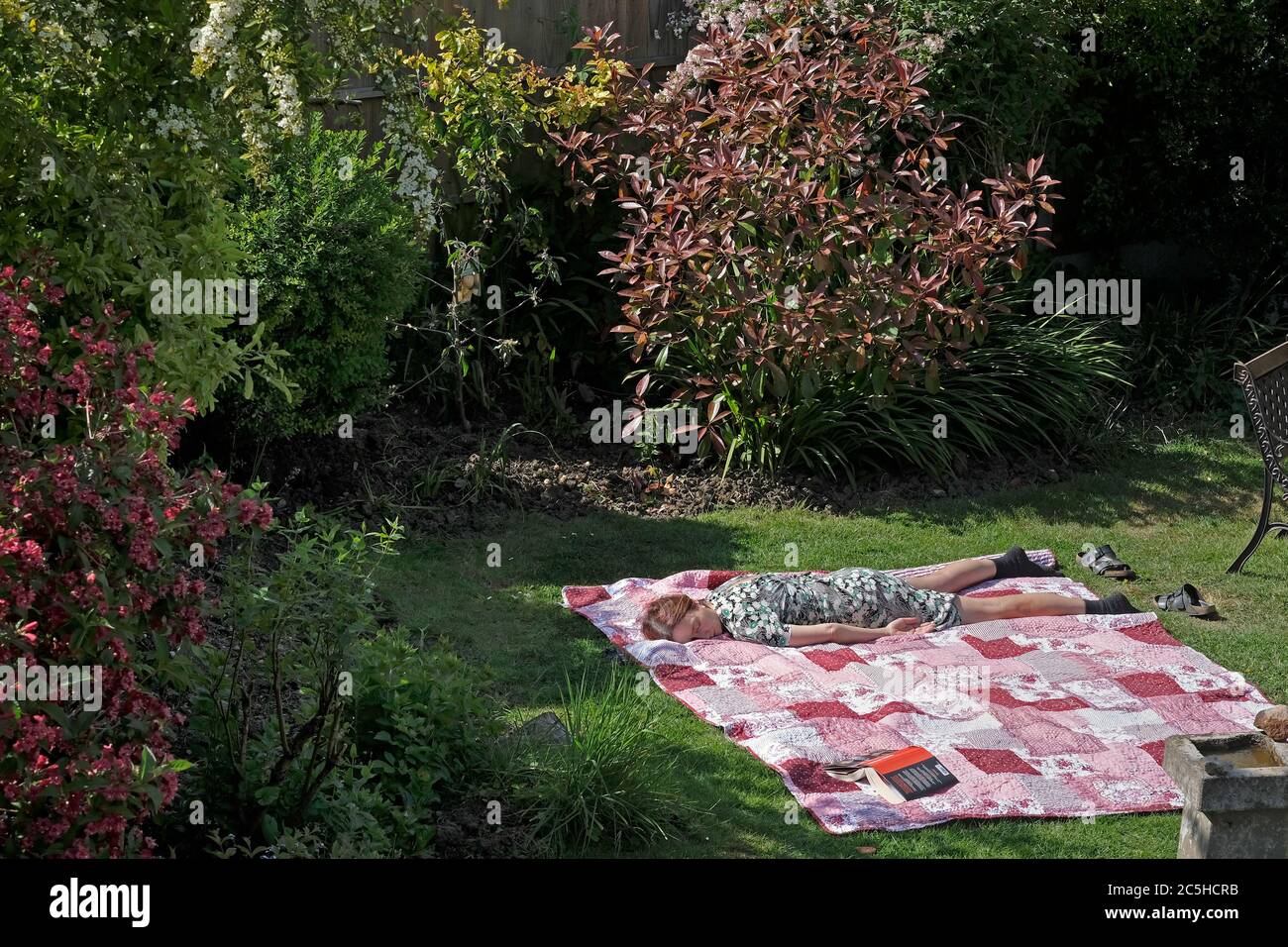 Eine Frau, die in ihrem Vorstadtgarten in Großbritannien schläft Stockfoto