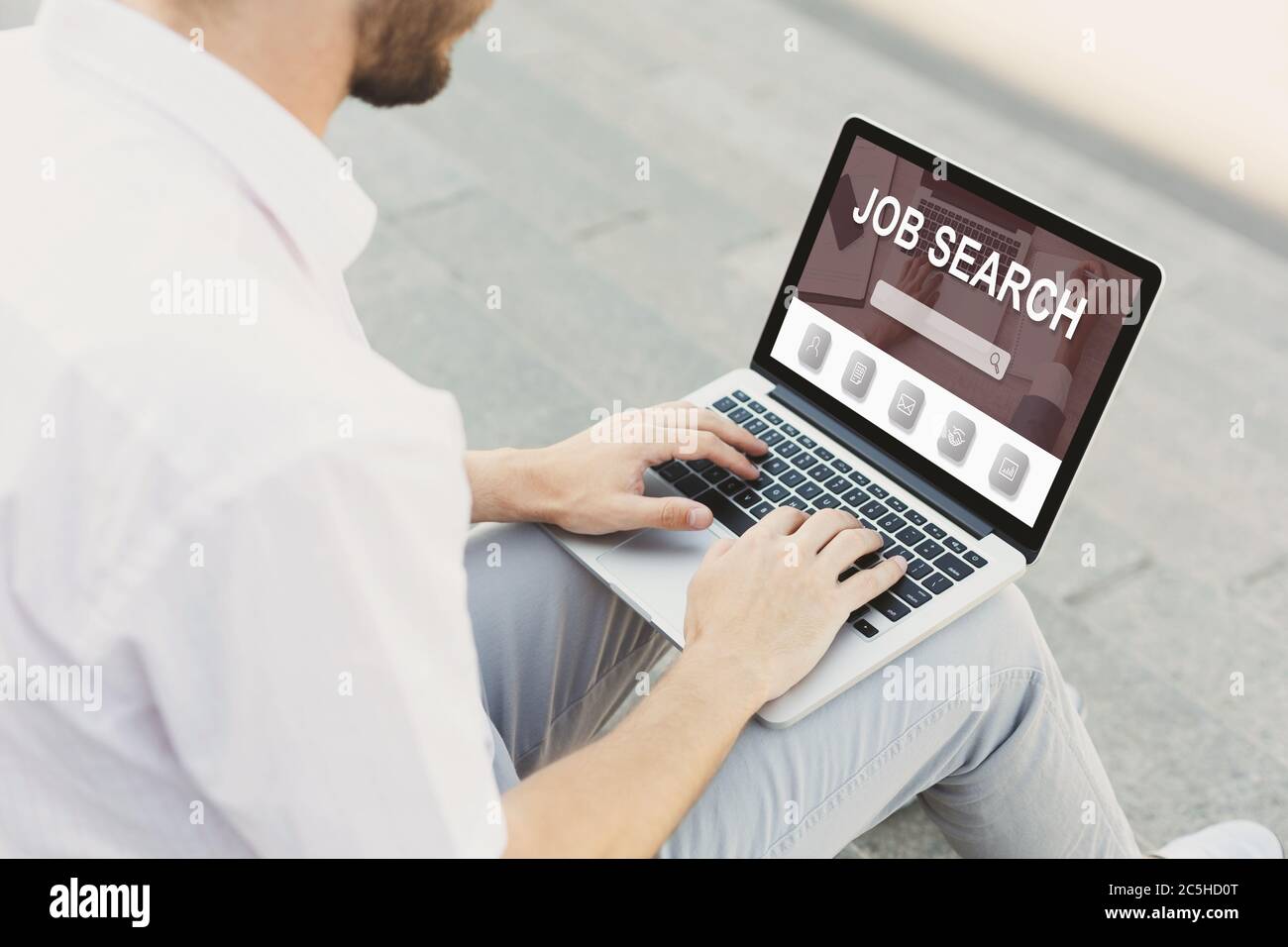 Kerl mit Laptop mit Job-Suchmaschine auf dem Bildschirm Stockfoto