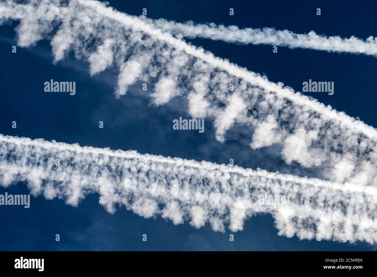 Die Kontragel mehrerer Flugzeuge gegen einen blauen Himmel. Symbolisches Foto für CO2, Klimawandel und Umweltschutz. Stockfoto