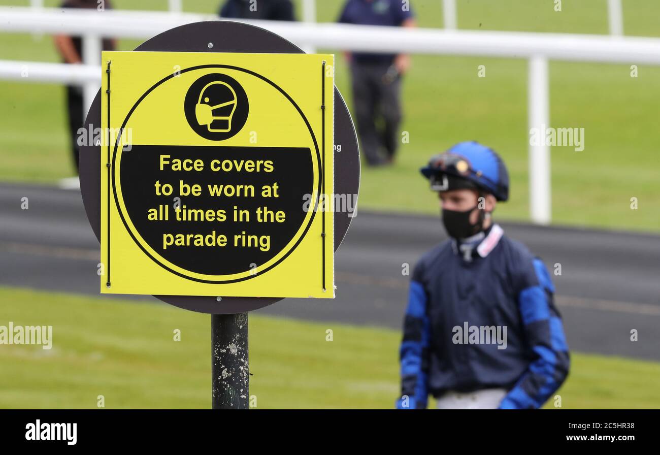 Jockey David Egan steht neben einem Schild, das das obligatorische Tragen von Gesichtsbezügen vor der ownersgroup.co.uk Novice Auktion Einsätze auf der Chepstow Racecourse durchgesetzt. Stockfoto