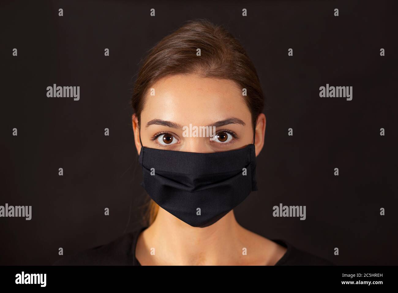Nahaufnahme eines Mädchens, das während einer Pandemie von Covid-19 eine schwarze Stoffmaske trägt. Stockfoto