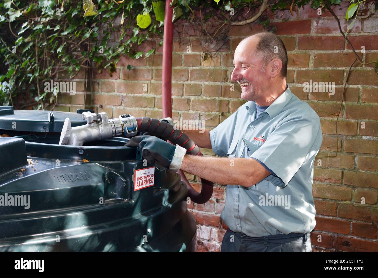 BUCKINGHAM, Großbritannien - 13. September 2014. Mann, der einen gebundenem Öltank mit Heizöl (Kerosin) in einem Haus im ländlichen England, Großbritannien, füllt Stockfoto