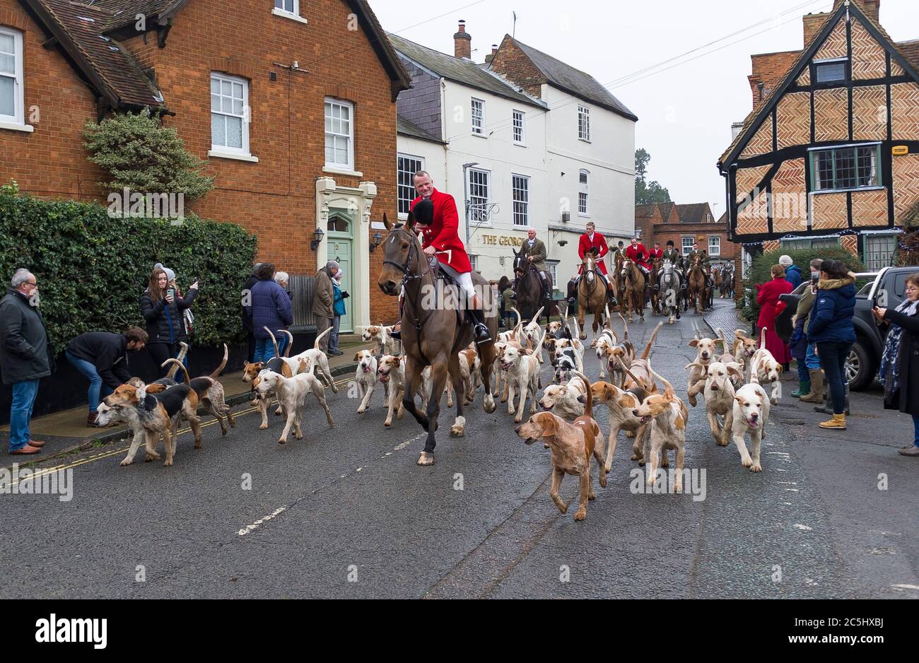 WINSLOW, Großbritannien - 26. Dezember 2018. Fuchsjagd, Männer in Kostümen reiten auf Pferden mit einem Rudel von Jagdhunden durch eine ländliche Stadt in Buckinghamshire, England Stockfoto