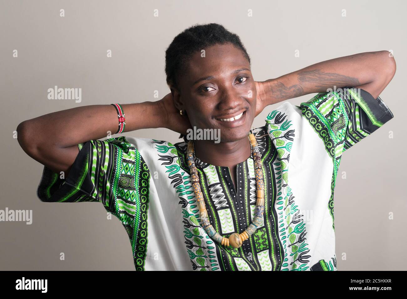 Glücklicher junger, schöner afrikanischer Mann mit Dreadlocks in traditioneller Kleidung Stockfoto