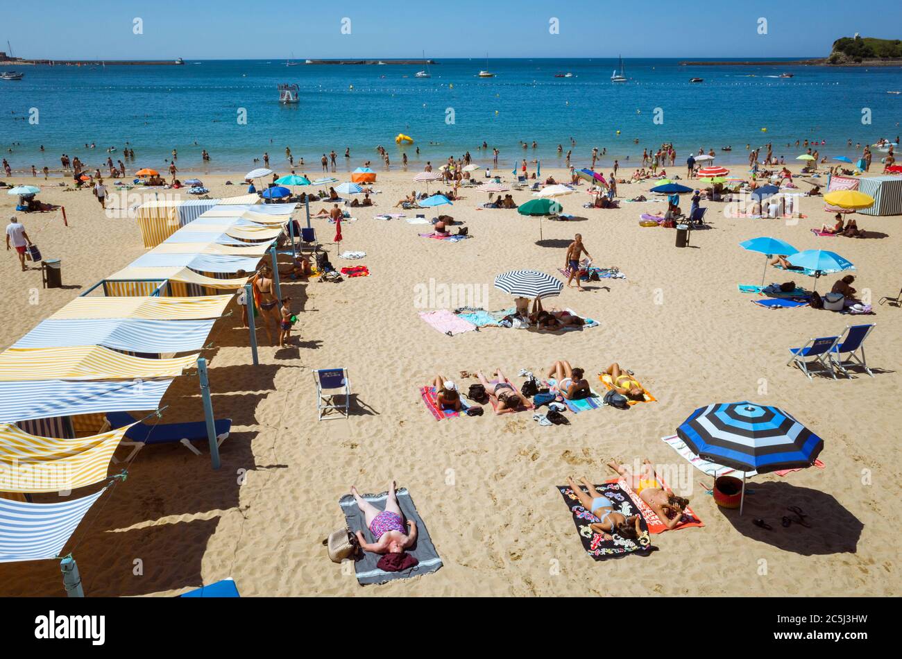Saint Jean de Luz, Französisch Baskenland, Frankreich - 19. Juli 2019 : Menschen sonnen sich am Strand an einem sonnigen Sommertag. Stockfoto